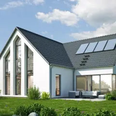 Nowoczesny dom modułowy z panelami słonecznymi na dachu, otoczony zielenią.